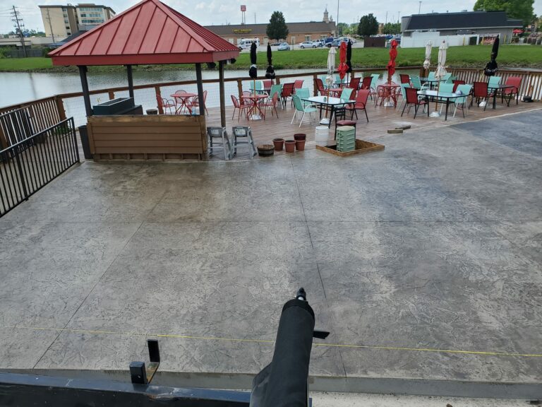 Large, stamped concrete patio with restaurant tables and chairs nearby
